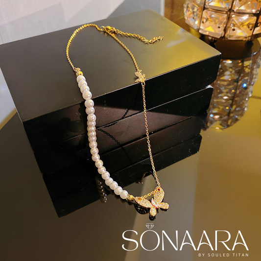 Pearl Butterfly Stainless Steel necklace with gold chain and butterfly pendant on a reflective surface, branded 'Sonaara'.