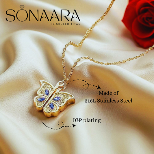 Gold butterfly necklace with blue stones on a beige fabric background, featuring the brand 'Sonaara'.