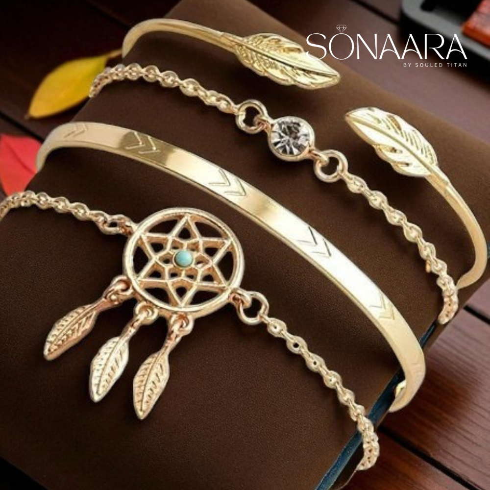 Gold bracelet with dreamcatcher design and feathers on a brown surface, branded 'Sonaara'.