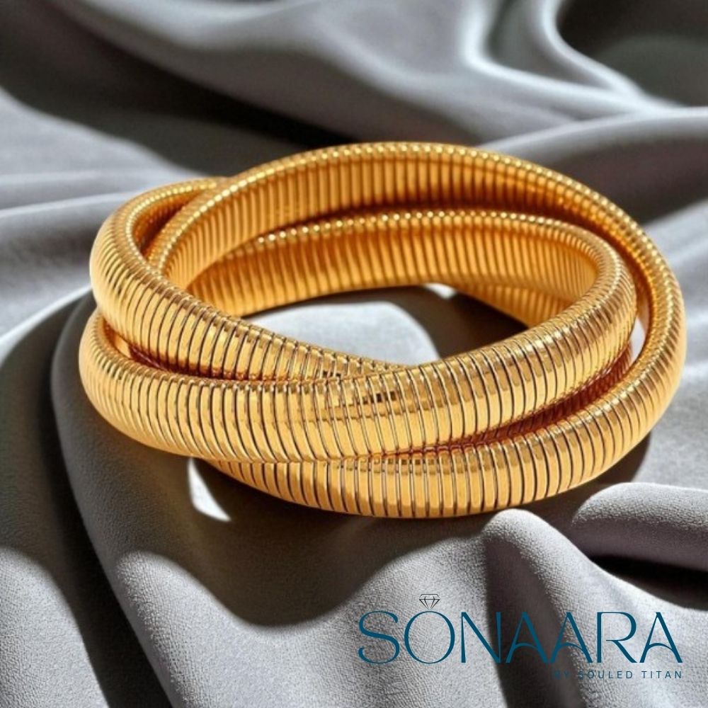 Gold bangles on a gray fabric background with 'Sonaara' branding.