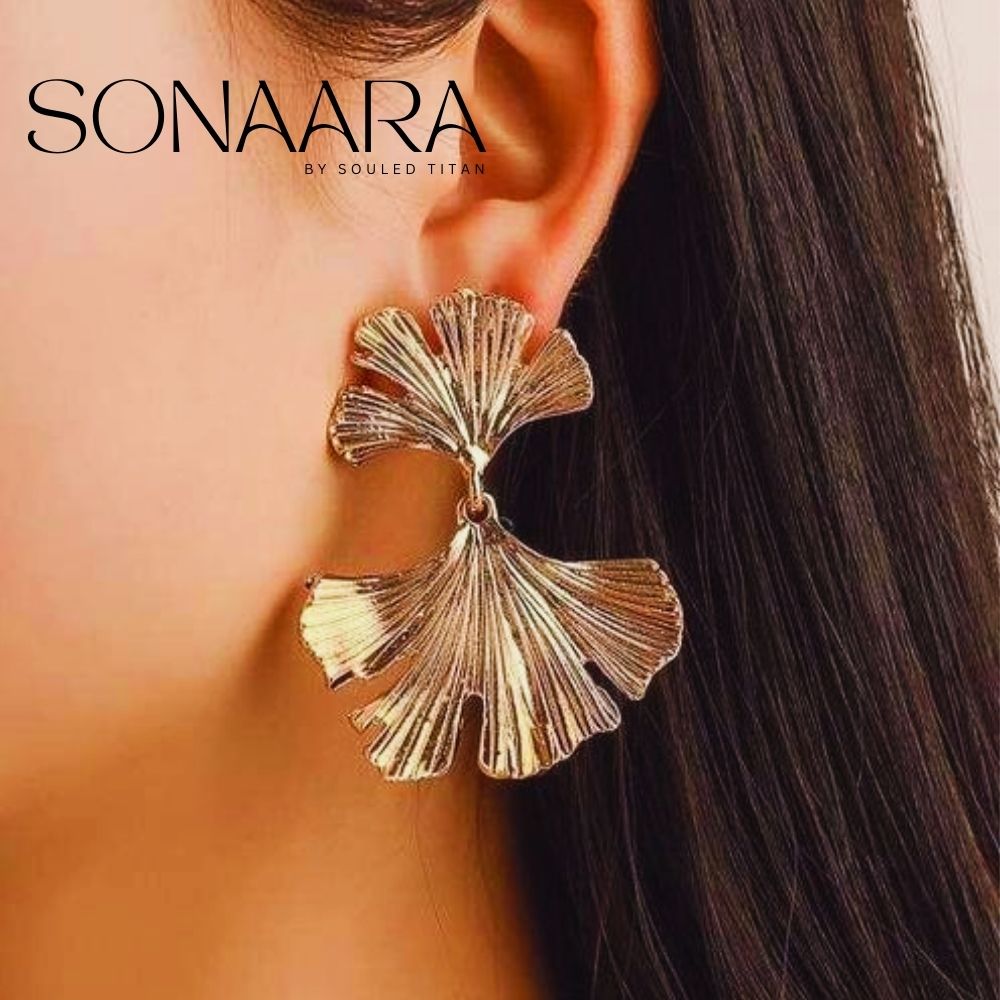 Gold leaf-shaped earring worn by a girl with 'Sonaara' branding.