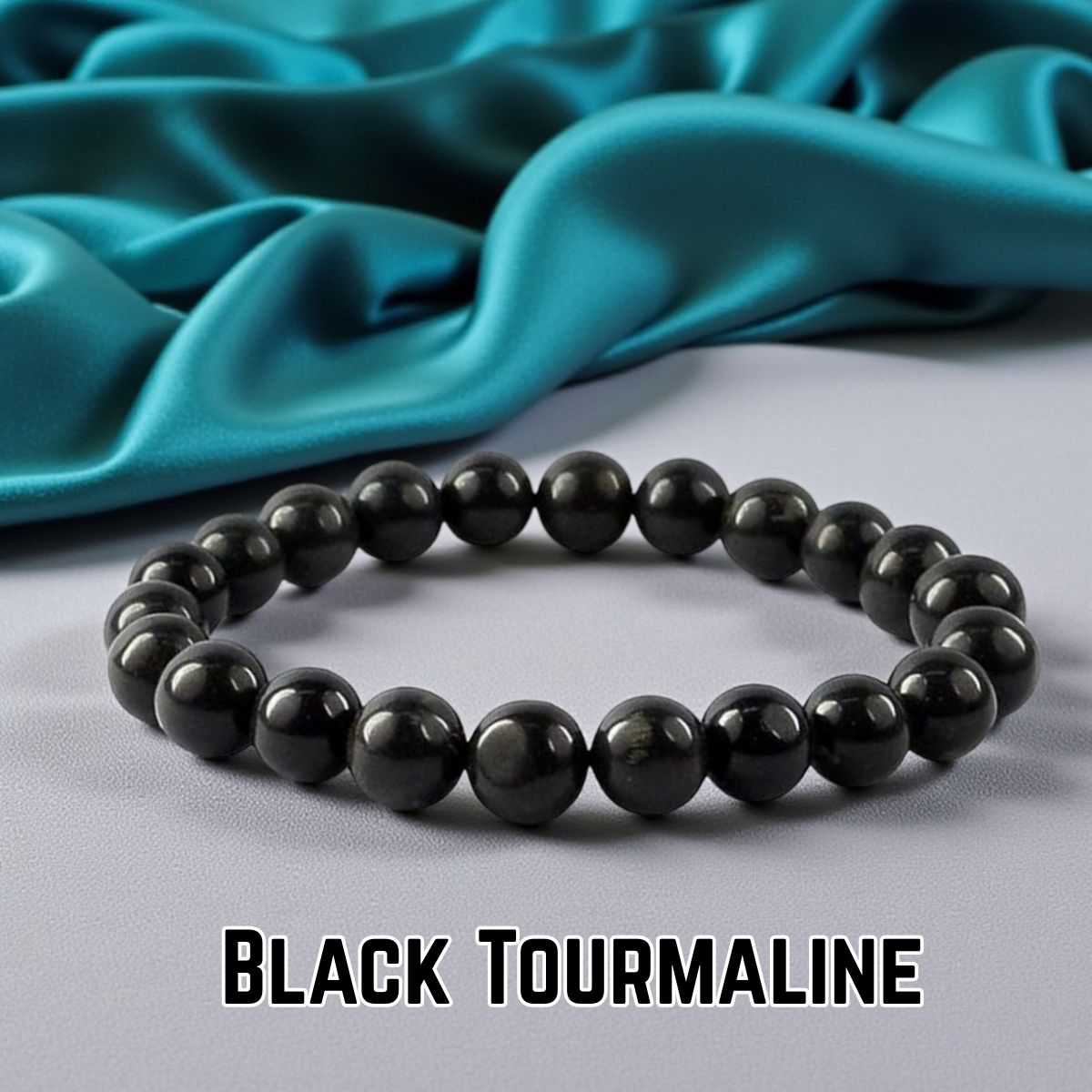 Black tourmaline bracelet on a gray surface with teal fabric in the background