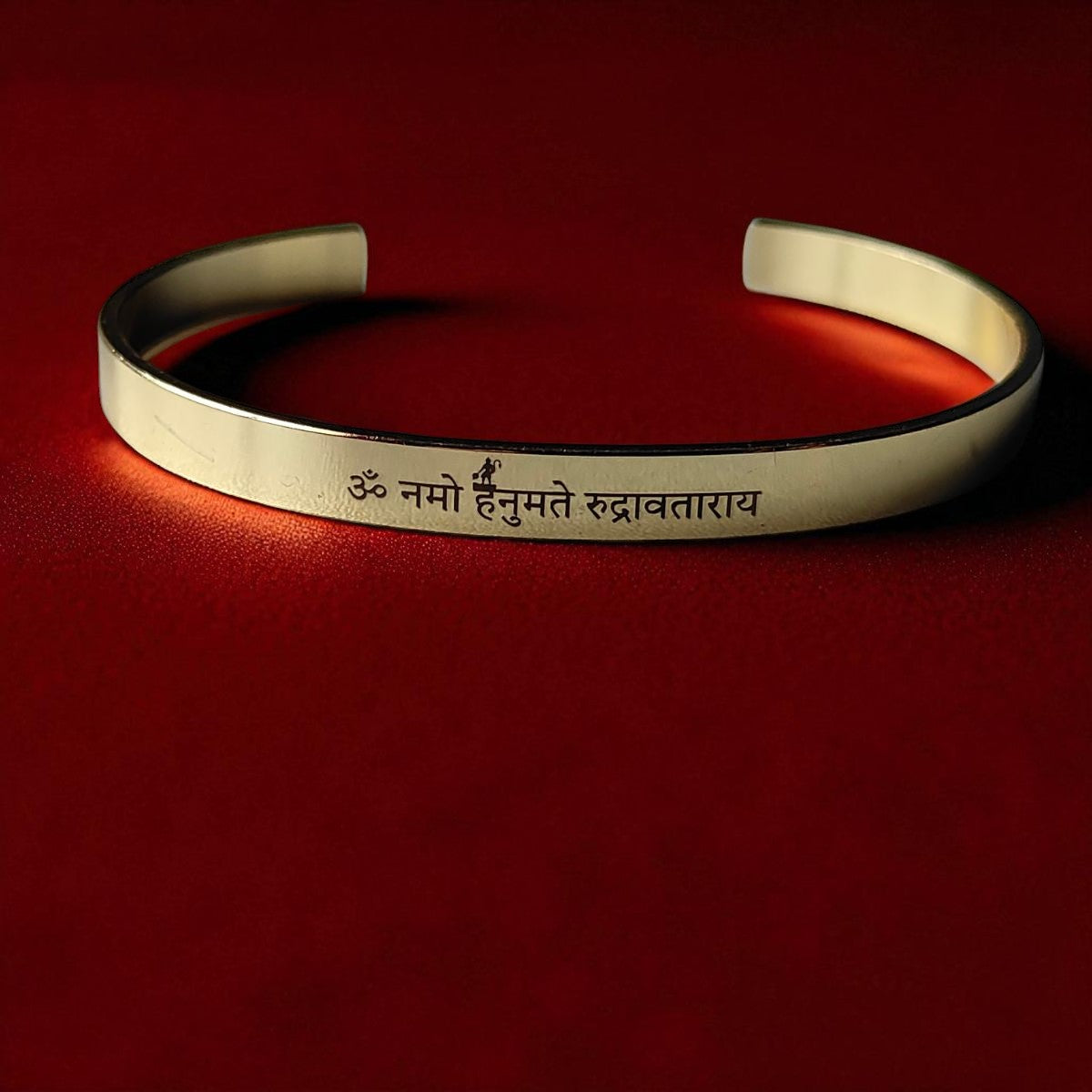 Golden bracelet with engraved Hnauman mantra on a red background