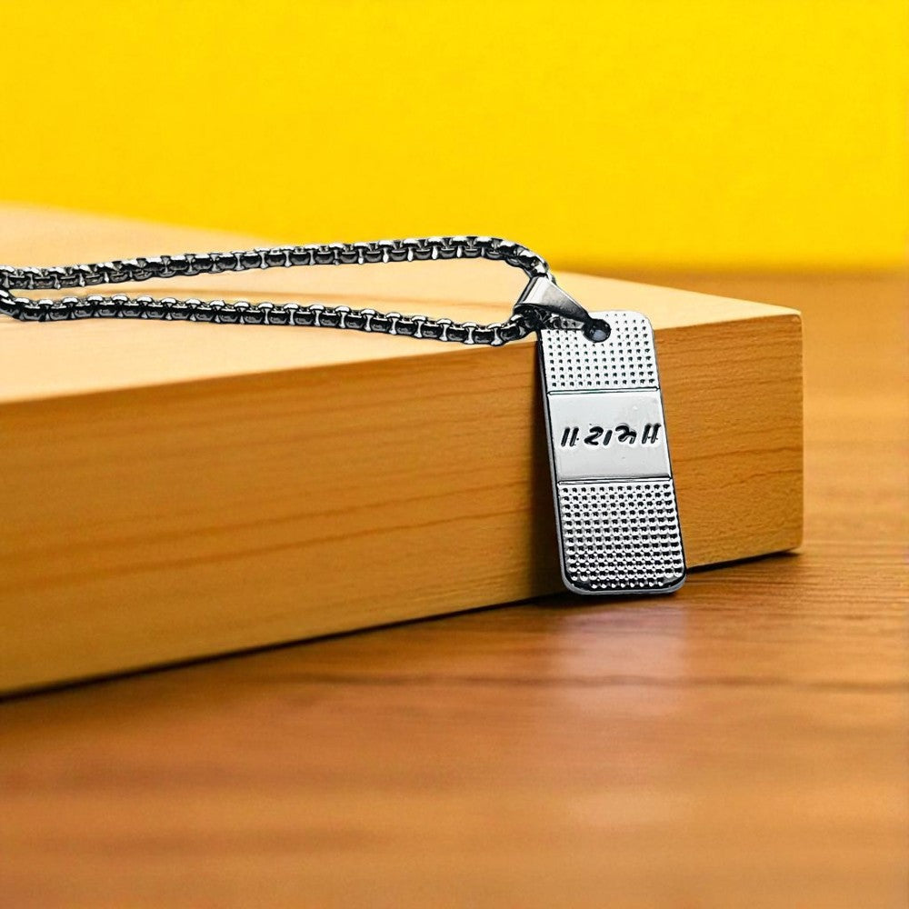 Silver Coated Ram engraved pendant with engraved text on a wooden surface against a yellow background