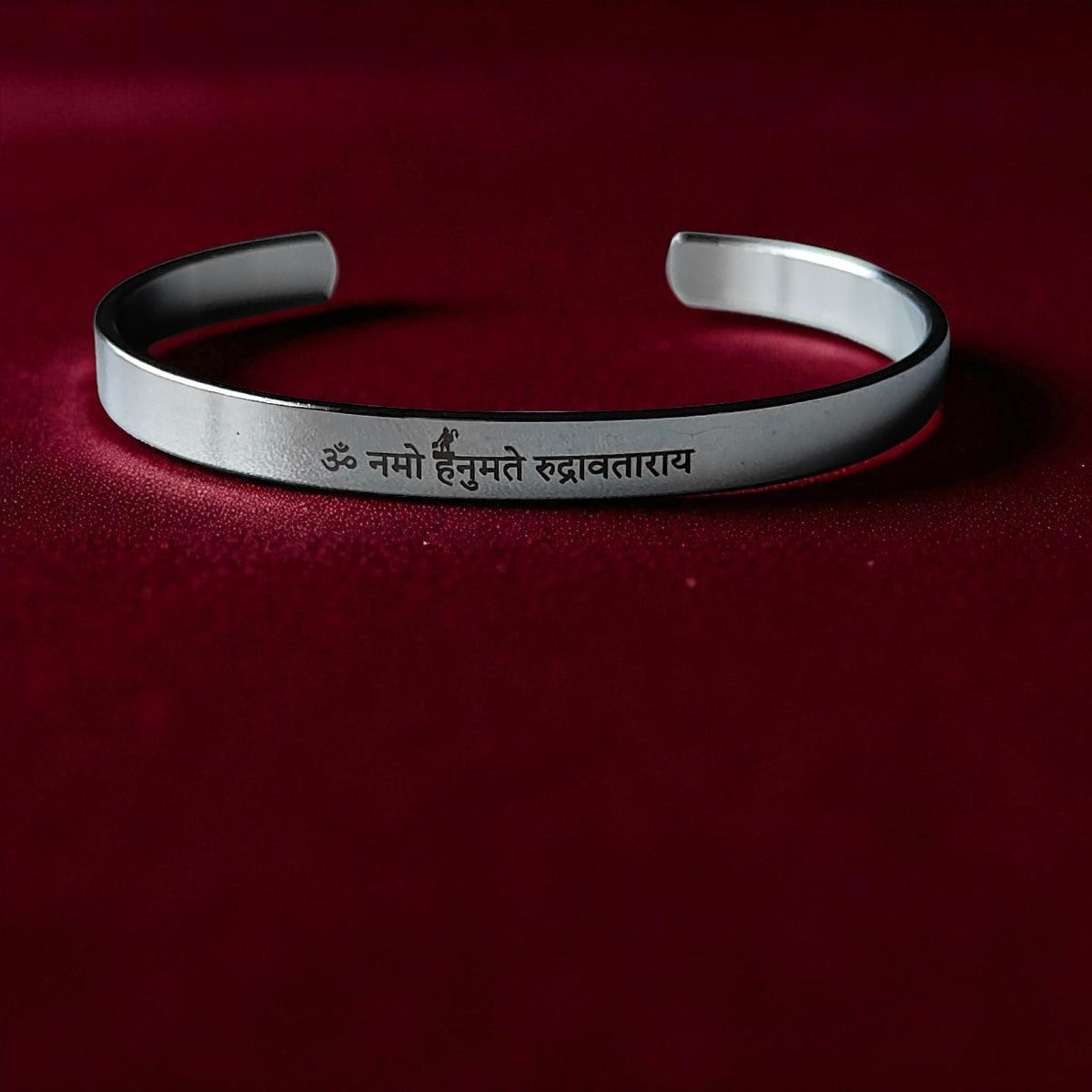 Silver kada for men with engraved hnauman mantra on a red background