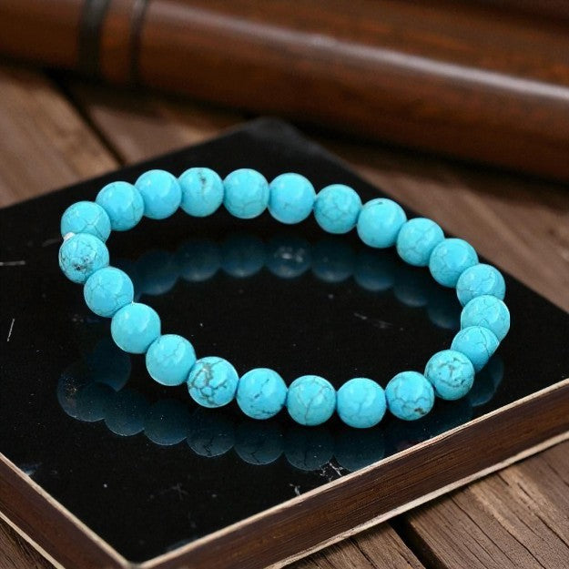 Turquoise beaded bracelet on a dark surface with a wooden background