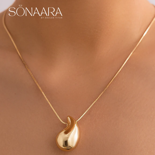 Gold necklace with a Tear Drop Charm on a mannequin, branded 'Sonaara by Souled Titan'.