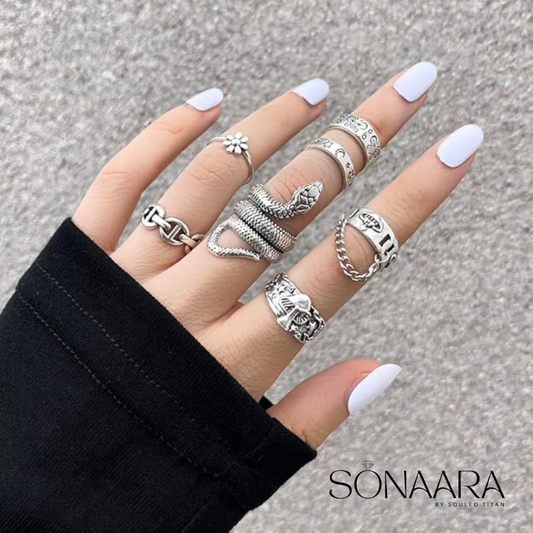 Hand wearing multiple silver rings with white nail polish on a neutral background, featuring the brand 'Sonaara'.