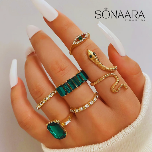 Hand wearing multiple rings with green gemstones and gold accents, branded 'Sonaara'.