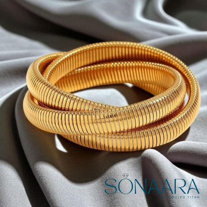 Gold bangles on a gray fabric background with 'Sonaara' branding.