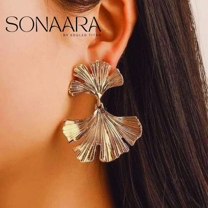 Gold leaf-shaped earring worn by a girl with 'Sonaara' branding.