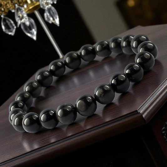 Black Tourmaline bracelet on a wooden surface with blurred decorative elements in the background