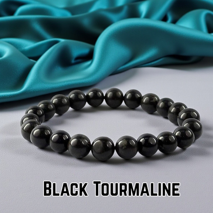 Black tourmaline bracelet on a gray surface with teal fabric in the background