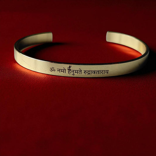 Golden bracelet with engraved Hnauman mantra on a red background