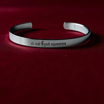 Silver kada for men with engraved hnauman mantra on a red background
